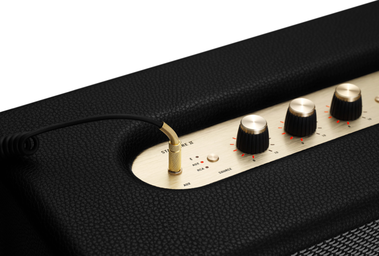Haut-parleur noir avec des accents dorés et un cordon noir avec connecteur doré pour l'entrée audio.