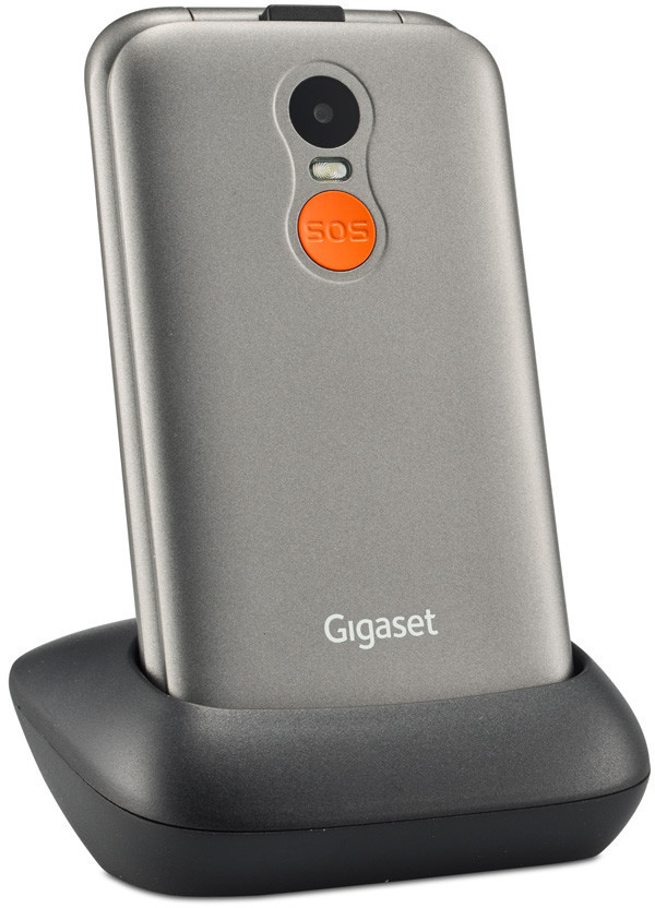 Un téléphone Gigaset gris repose dans un socle de chargement noir. Il possède une caméra et un bouton SOS orange à l'arrière.