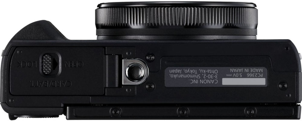 Zwarte Canon camera, onderaanzicht. Heeft een open poort voor kaart/batterij en technische gegevens.