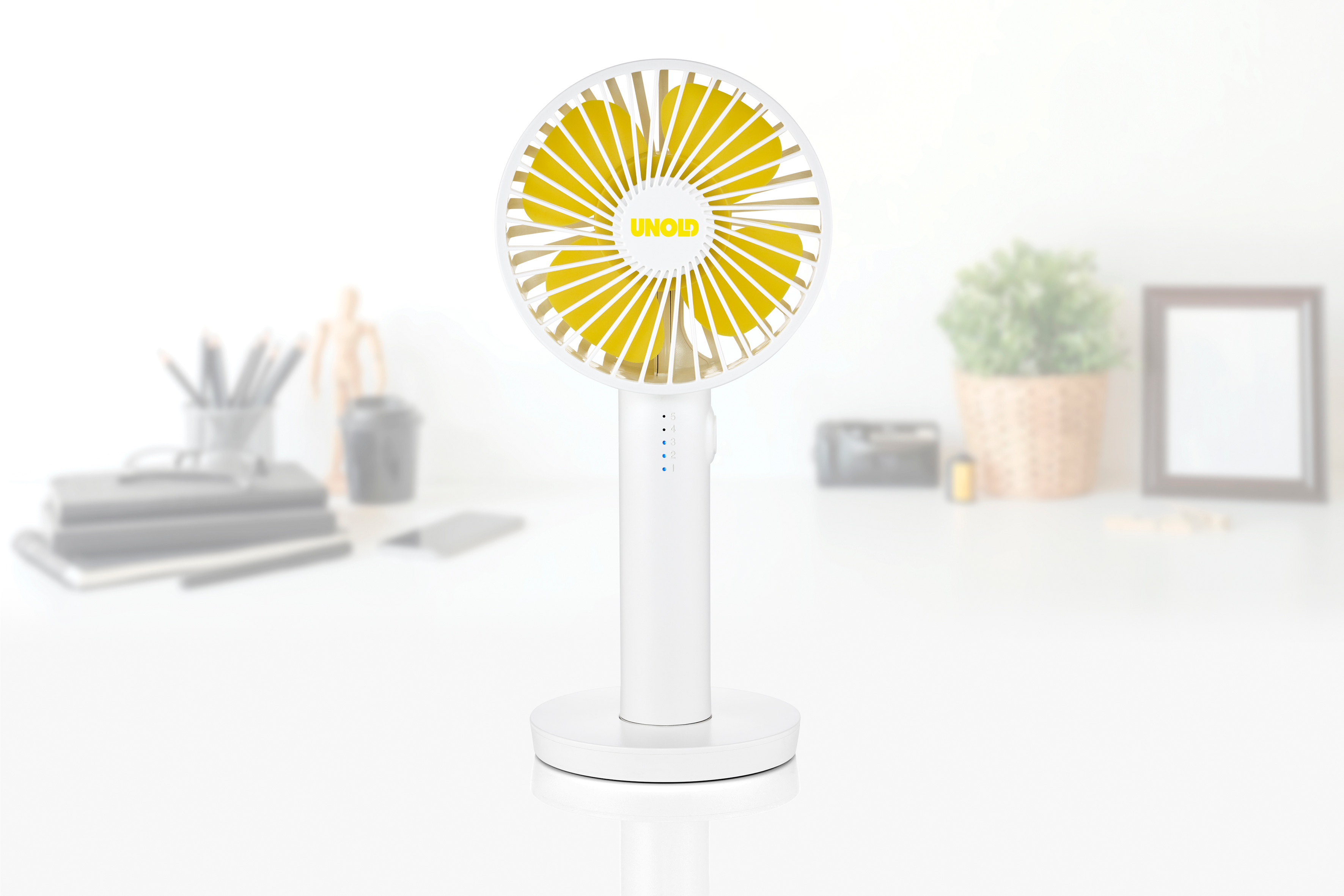 Ein weißer Tischventilator mit gelben Rotorblättern steht auf einem Schreibtisch.