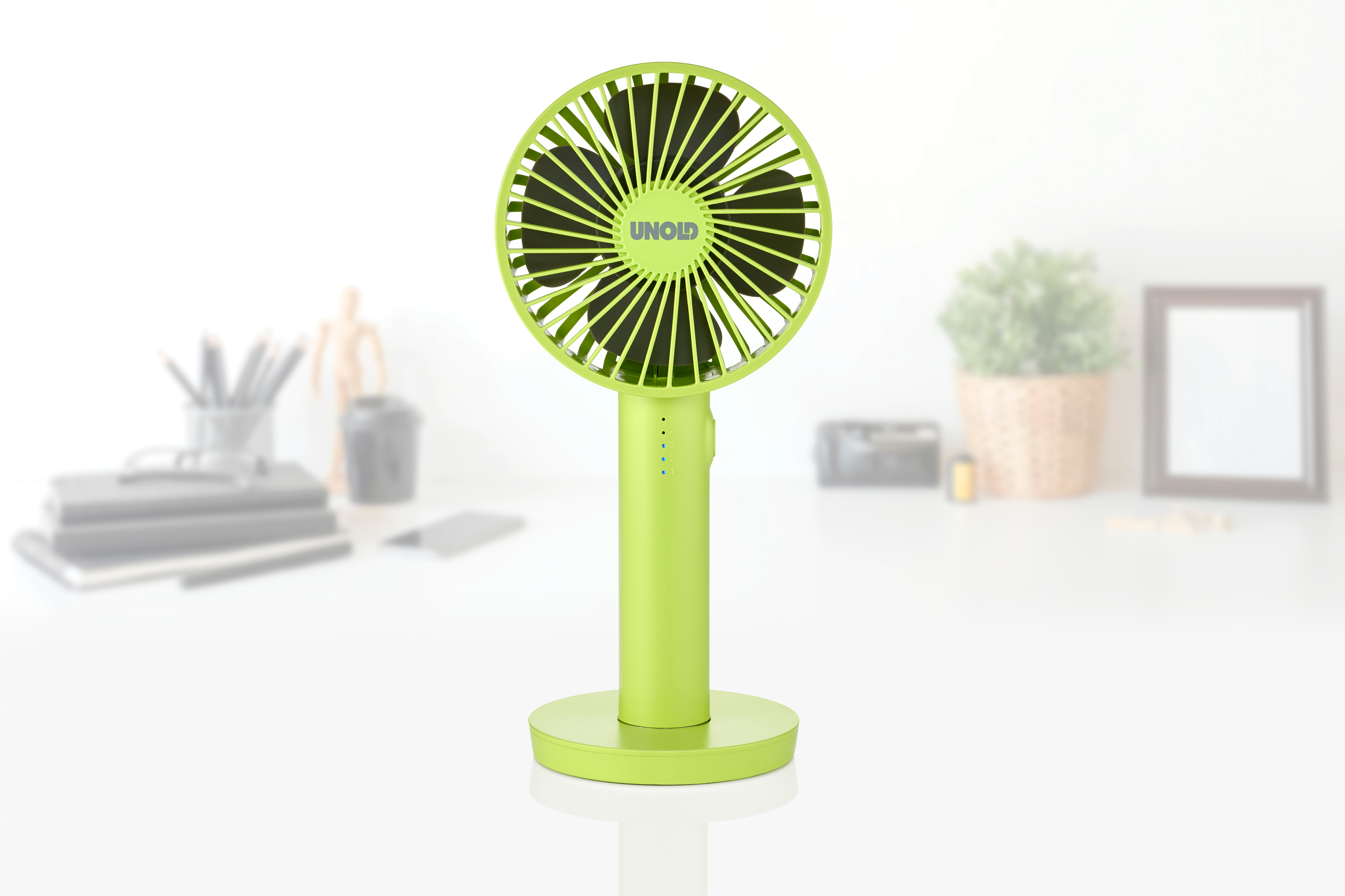 Ein kleiner, neongrüner Ventilator mit schwarzen Rotorblättern steht auf einem runden Sockel.