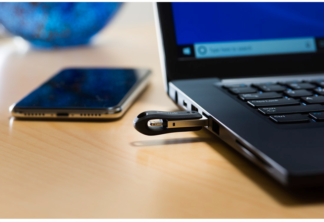 Laptop, telefoon en USB-stick op een houten bureau, verbonden, tech setup.