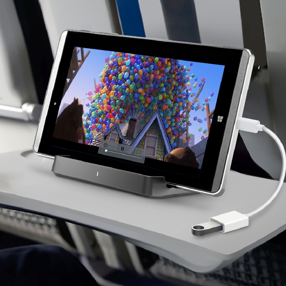 Tablet op een dienblad dat een film met ballonnen afspeelt, aangesloten op een oplader en een witte kabel.