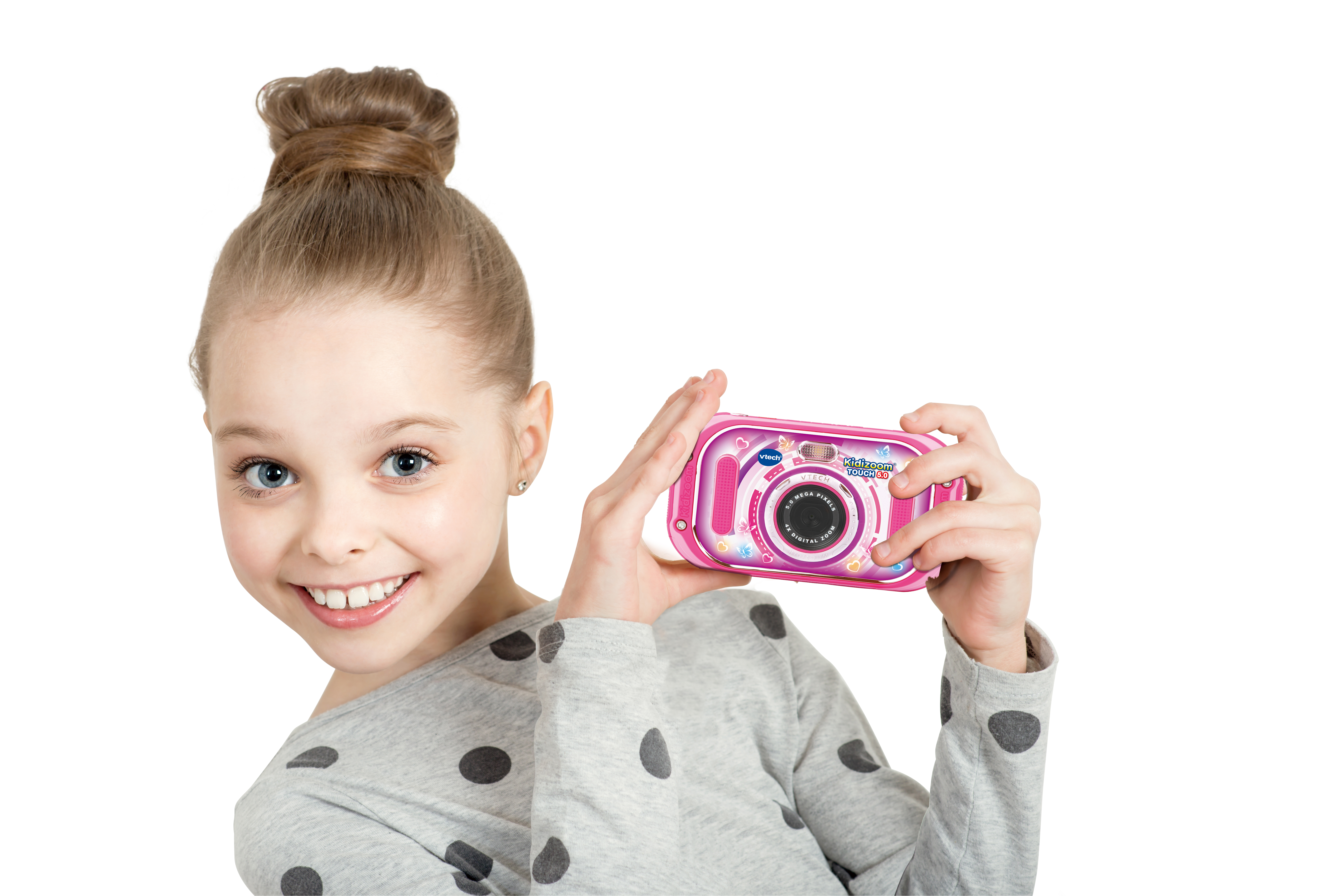 Ein junges Mädchen hält eine rosa Digitalkamera und lächelt den Betrachter an, weißer Hintergrund.