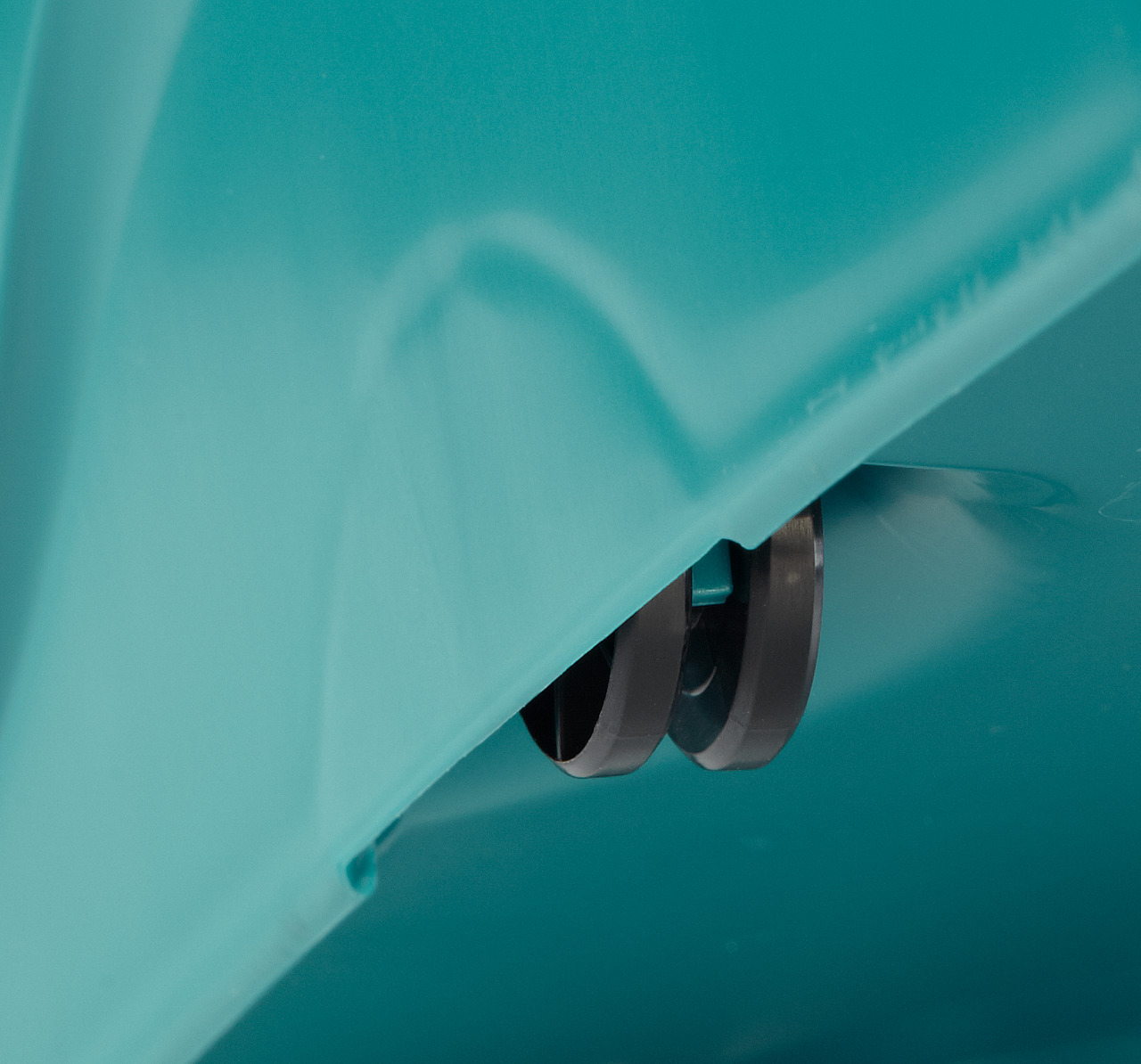 Gros plan de roues montées sur une surface turquoise, suggérant une partie d'un appareil.