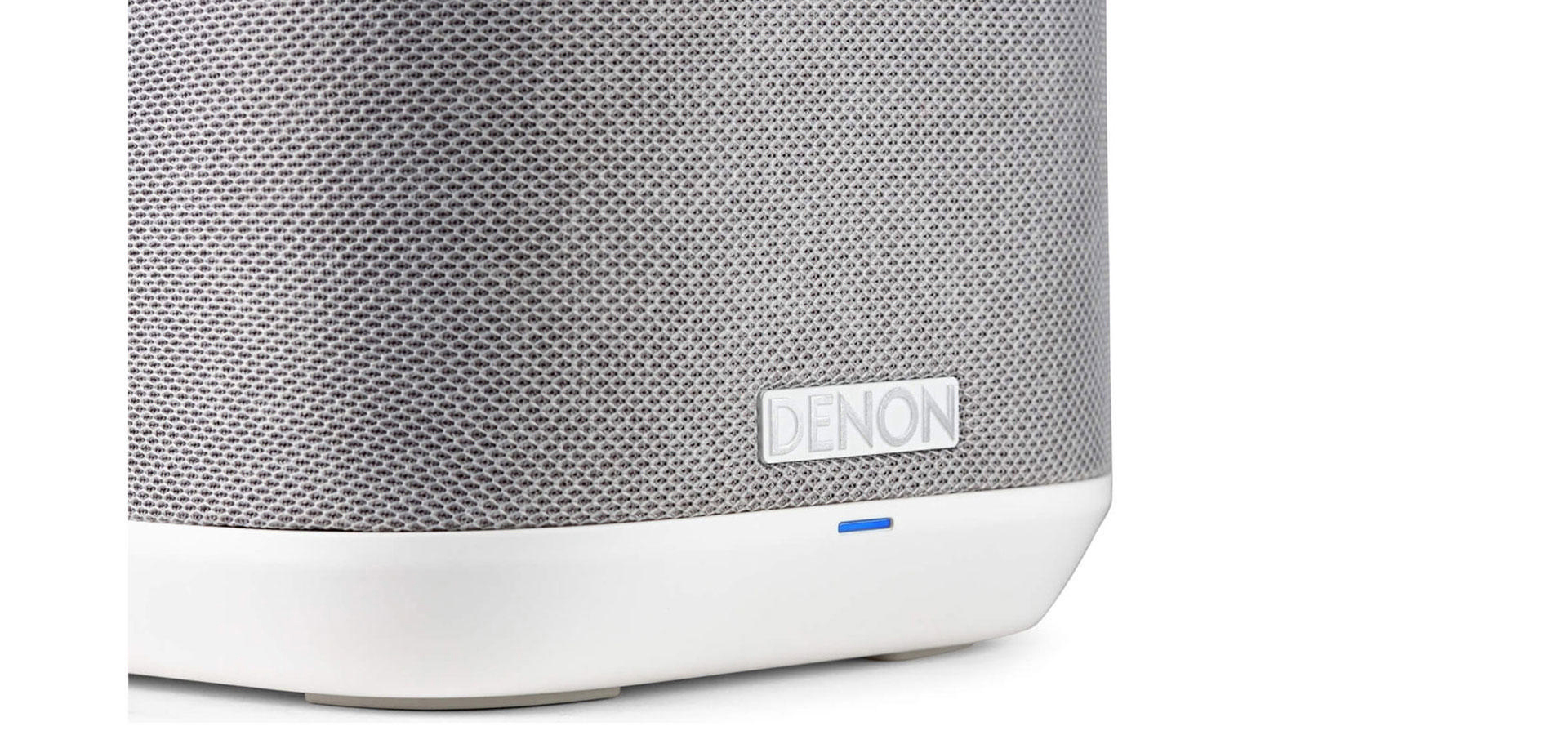 Ein weißer Lautsprecher mit grauem Mesh, Denon-Logo und blauem Licht.