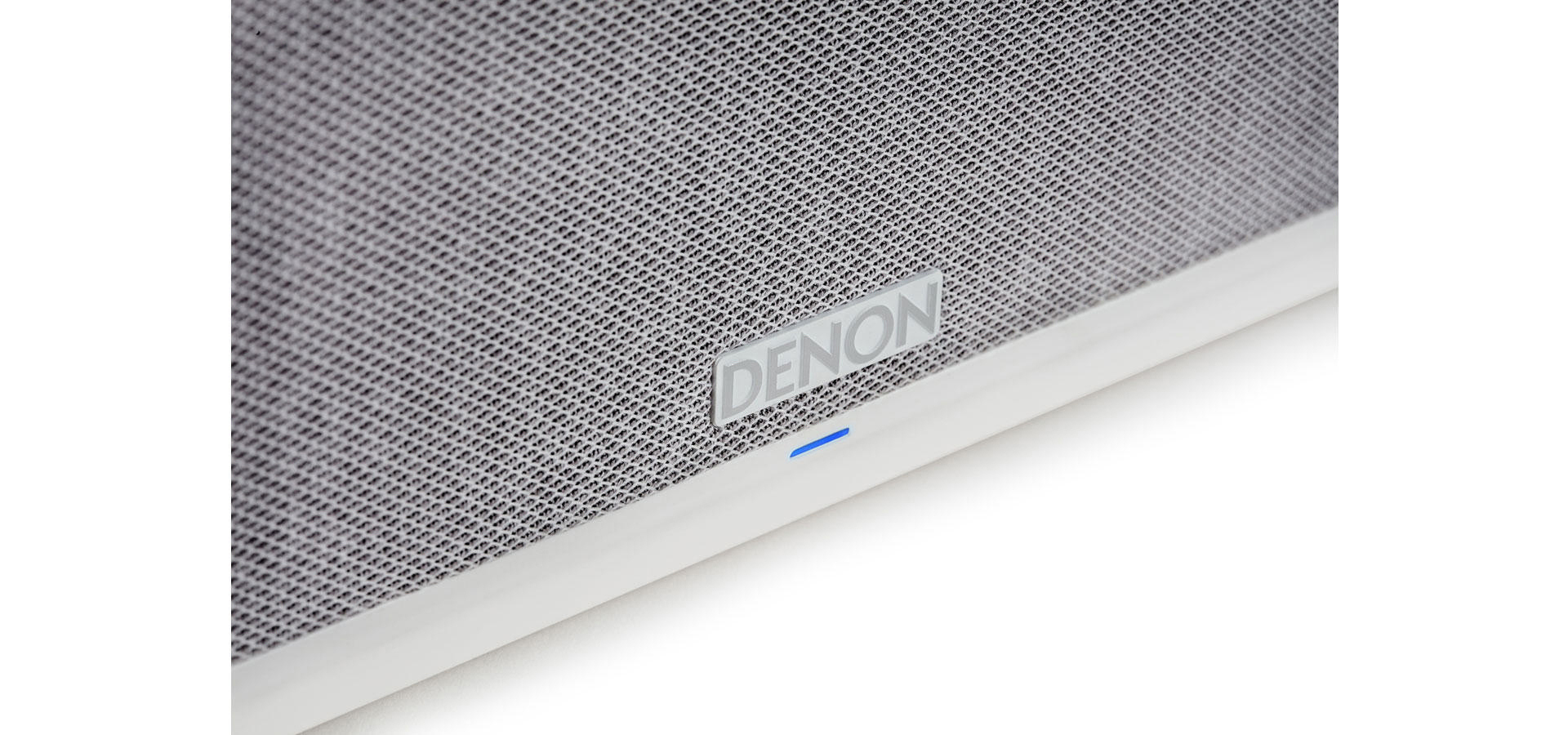 Nahaufnahme eines weißen Lautsprechers mit Denon-Logo und blauer Anzeige.
