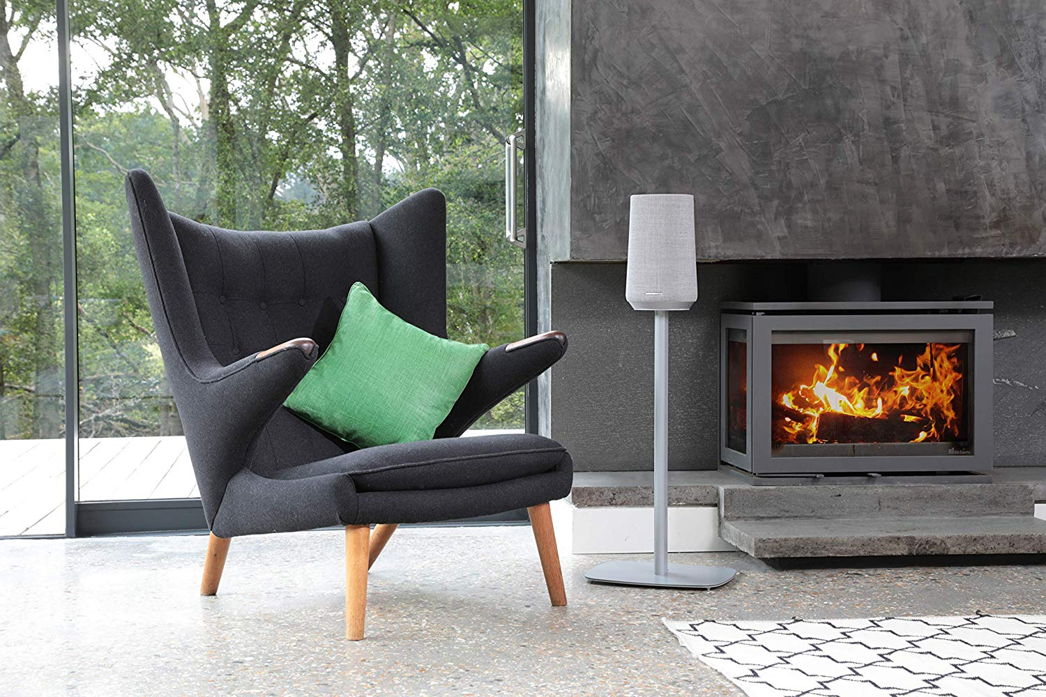 Interieur: grijze fauteuil, groen kussen, open haard, luidspreker op standaard.
