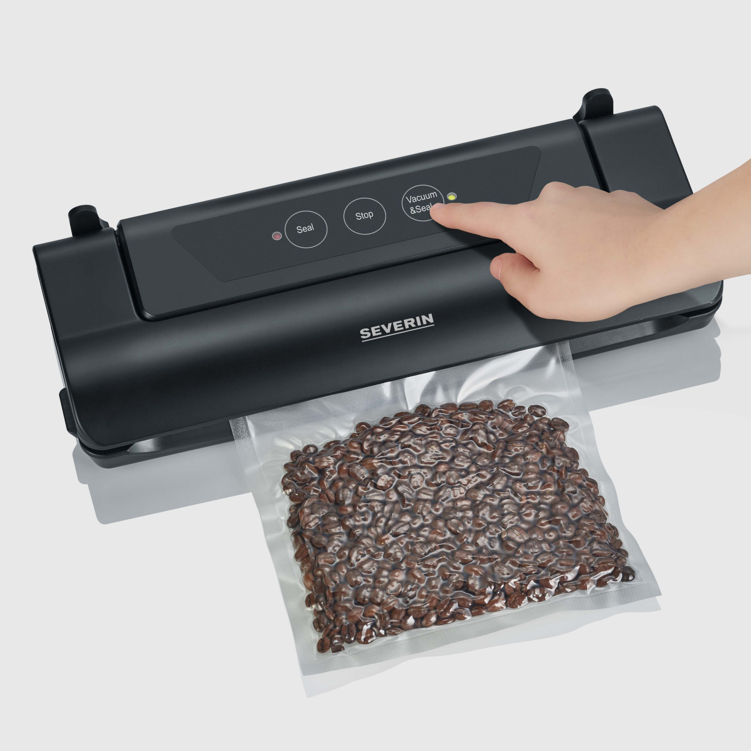 Een persoon gebruikt een zwarte vacuümsealer om een zak koffiebonen te sealen.