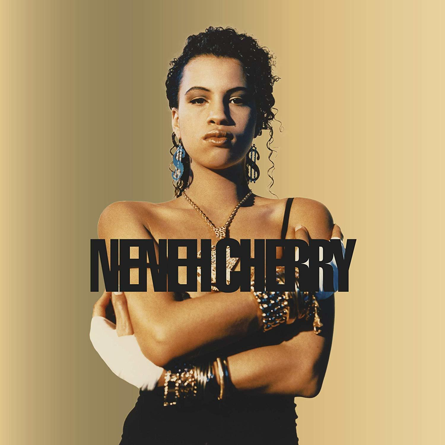 Egy göndör hajú nő, karba tett kézzel, fekete felsőben. A szöveg Neneh Cherry-t ír.