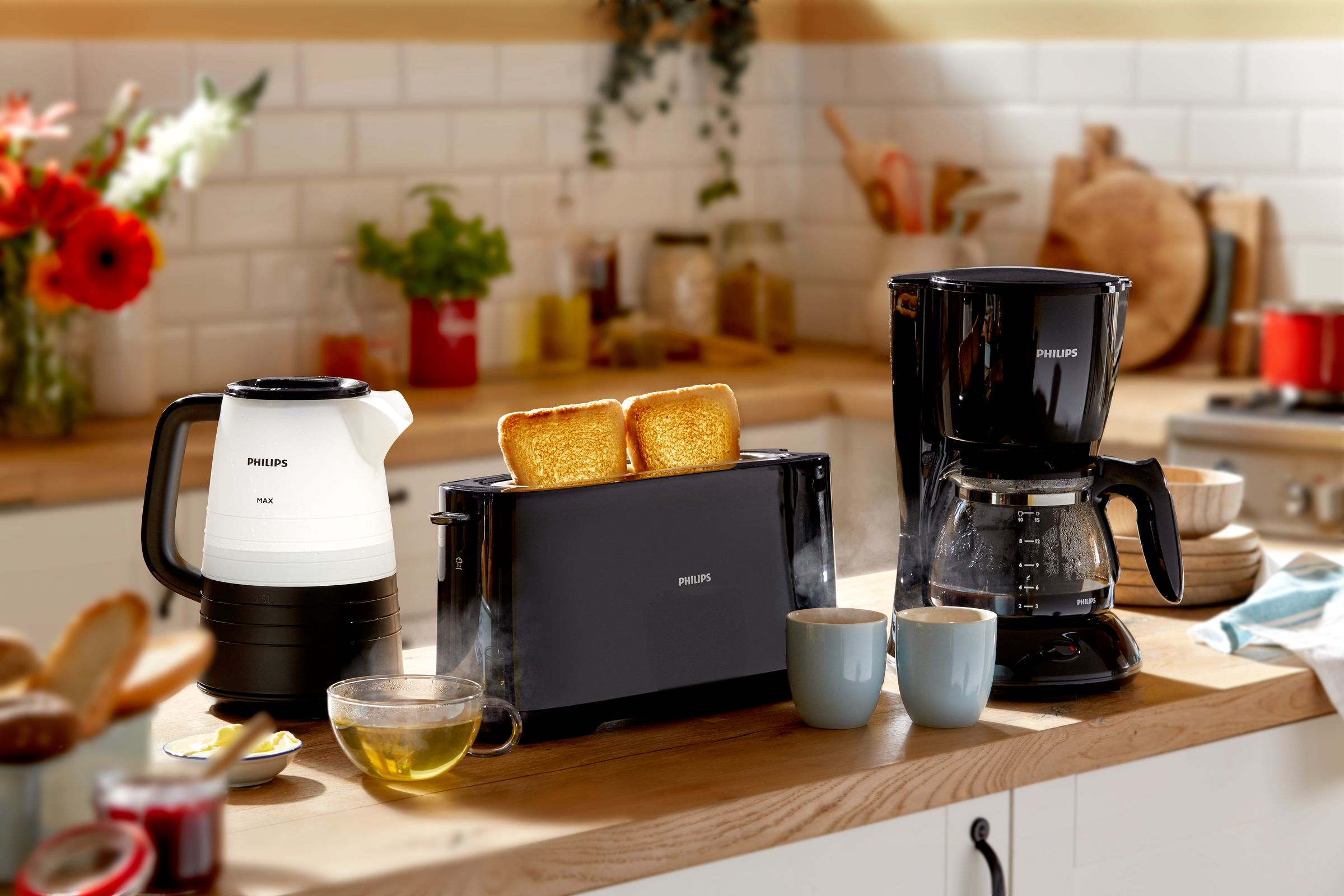 Kitchen appliances. Toaster with bread, coffee maker, and kettle on a wooden counter.