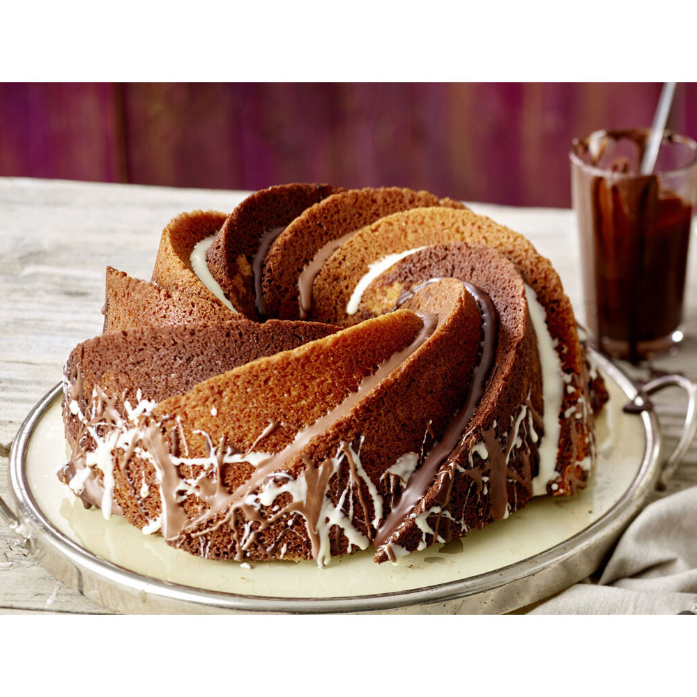 Ein Gugelhupf mit Schokoladen- und weißem Zuckerguss auf einer silbernen Platte mit einem Getränk.