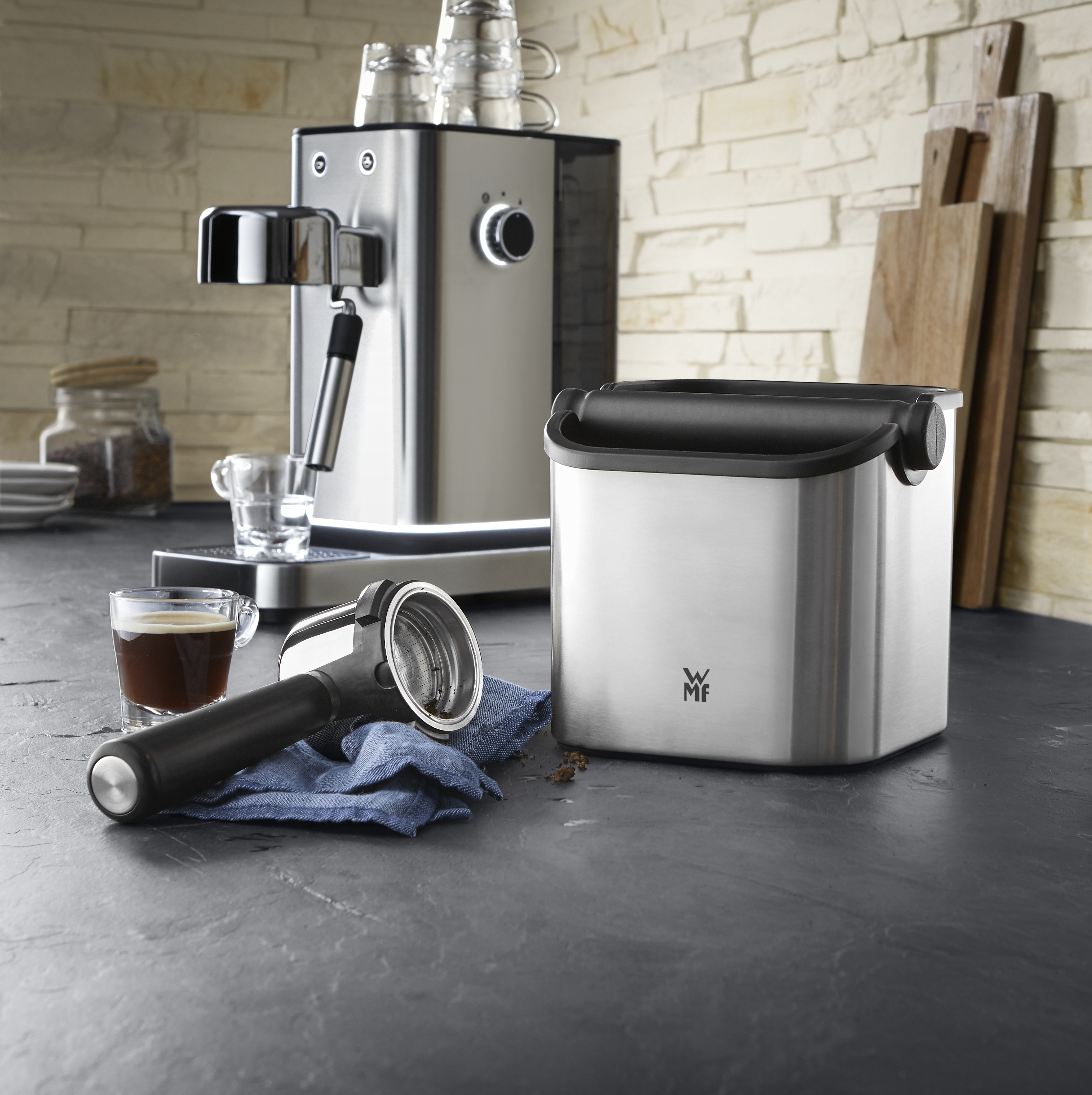 Espressomaschine, Mühle und Zubehör auf einer dunklen Theke.