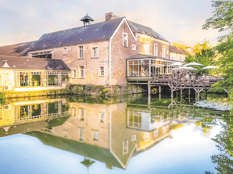 Edificio con riflesso nell'acqua, ponte e alcuni alberi verdi.