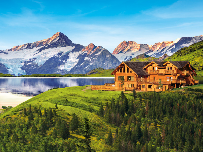 Casa su una collina con vista su un lago e montagne.