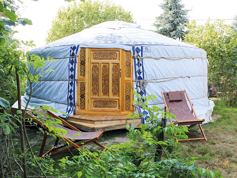 Una yurta con porta in legno e due sedie.
