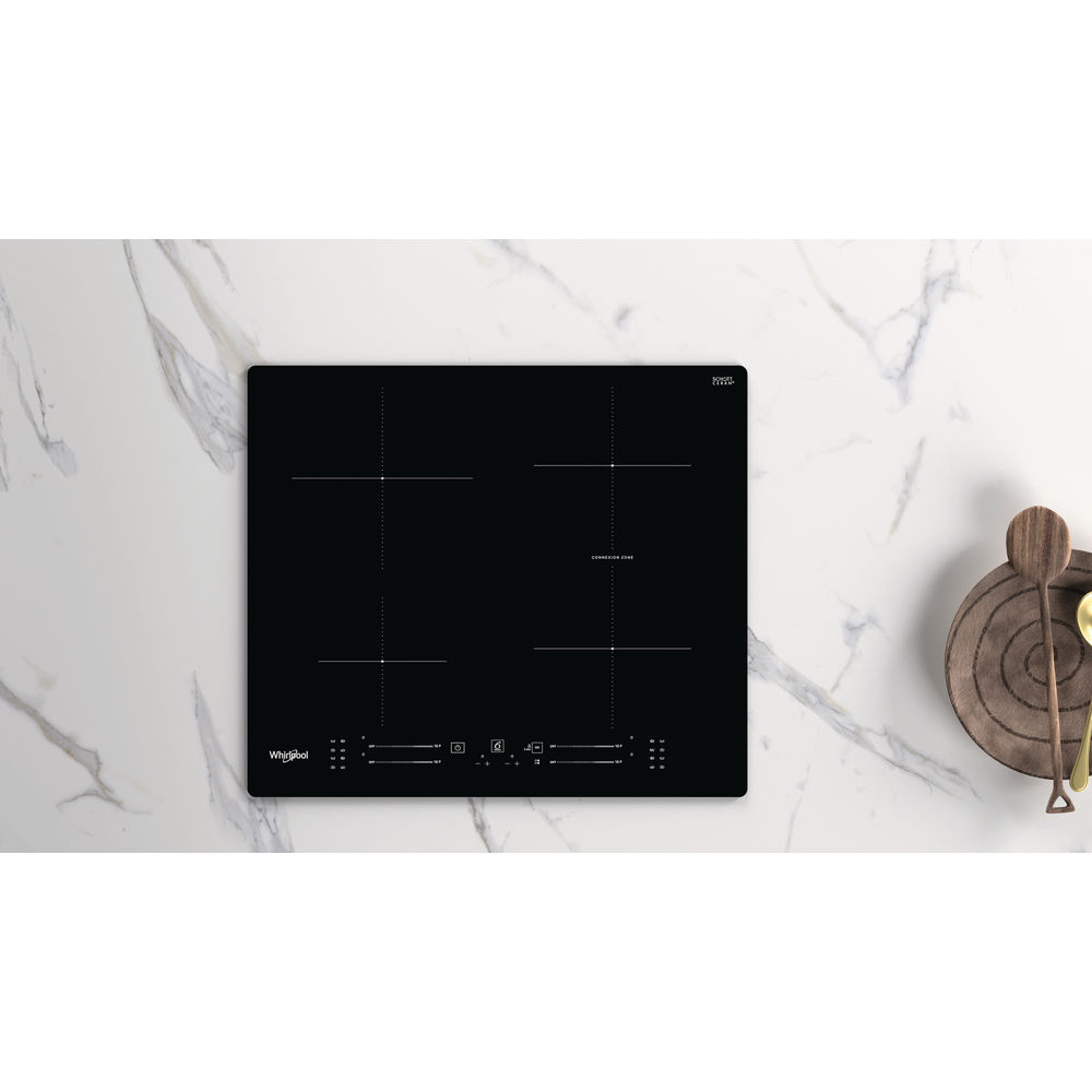 Table de cuisson à induction noire avec quatre brûleurs sur marbre blanc.