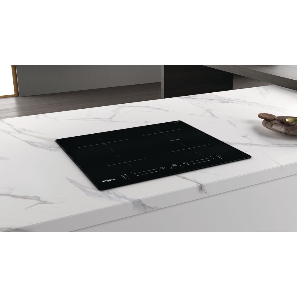 Une plaque de cuisson électrique noire sur un comptoir en marbre blanc. La plaque a quatre brûleurs.