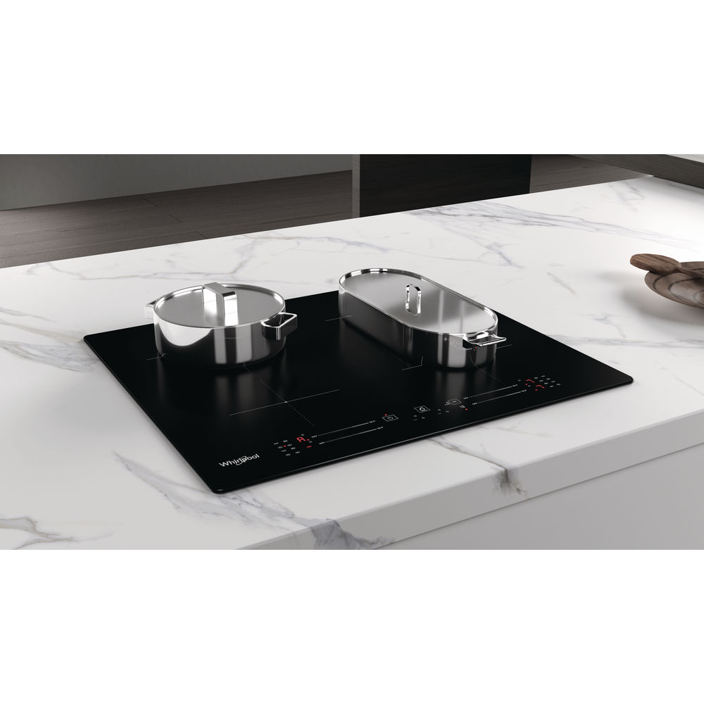 Une table de cuisson à induction Whirlpool noire avec deux casseroles sur un comptoir en marbre blanc.