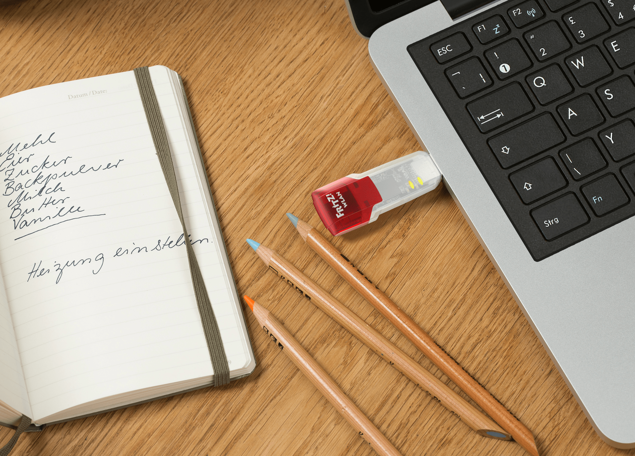 Bloc-notes, crayons et une clé USB branchée sur un ordinateur portable.