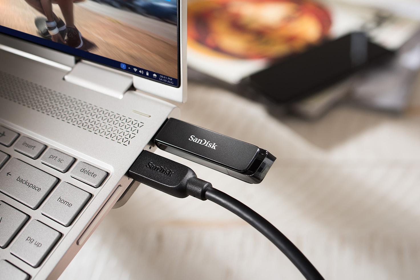 Ein Laptop mit einem Sandisk USB-Laufwerk, das mit einem Kabel angeschlossen ist.