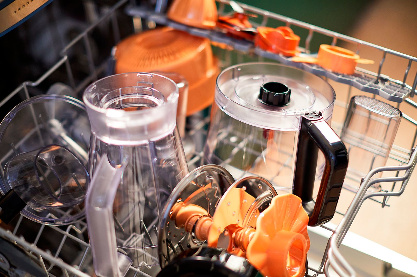 Geschirrspülergestell mit transparenten und orangenen Küchenmaschinen-Teilen.