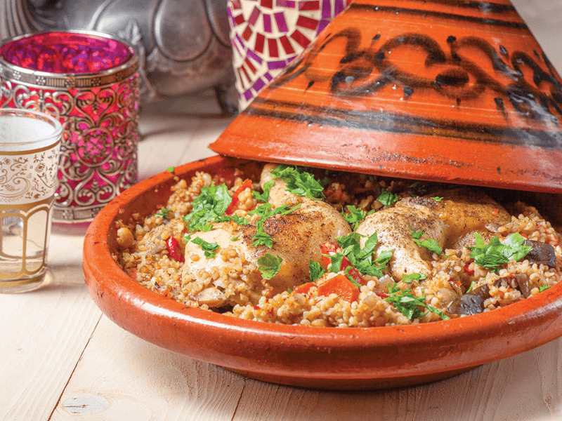 Plat tajine avec nourriture. Poulet et légumes, avec herbes. Table en bois.