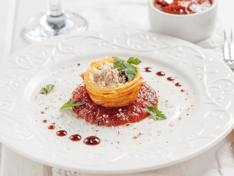 Elegante piatto con presentazione di cibo, salsa rossa e guarnizione.