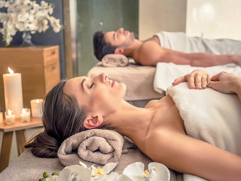 Una coppia sdraiata su lettini da massaggio in una spa.
