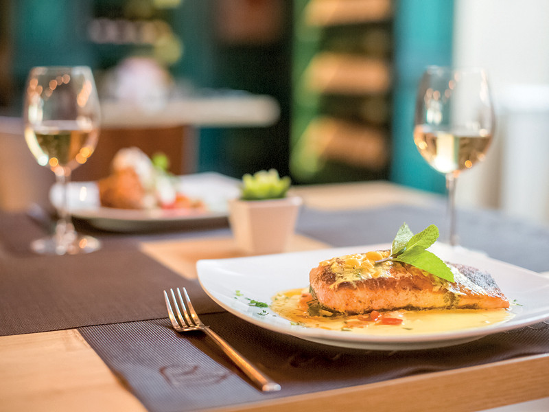 Lachs auf einem weißen Teller mit zwei Gläsern Weißwein.