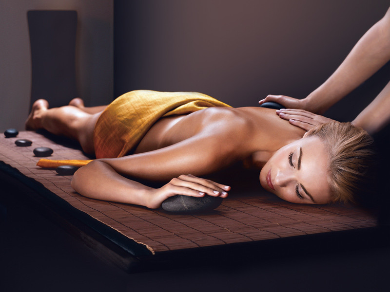 Une femme est allongée sur une table de massage avec des pierres chaudes.