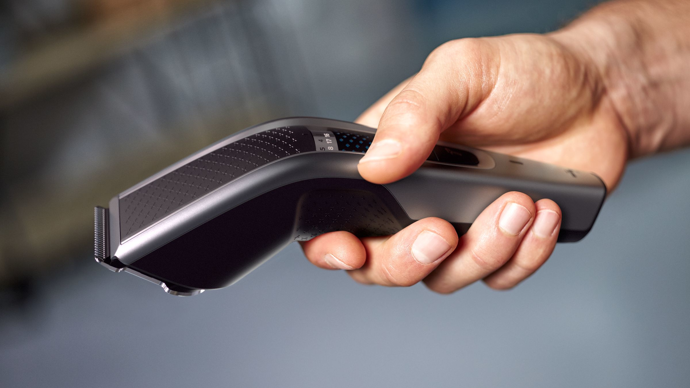 Hand holding a black Philips hair clipper.