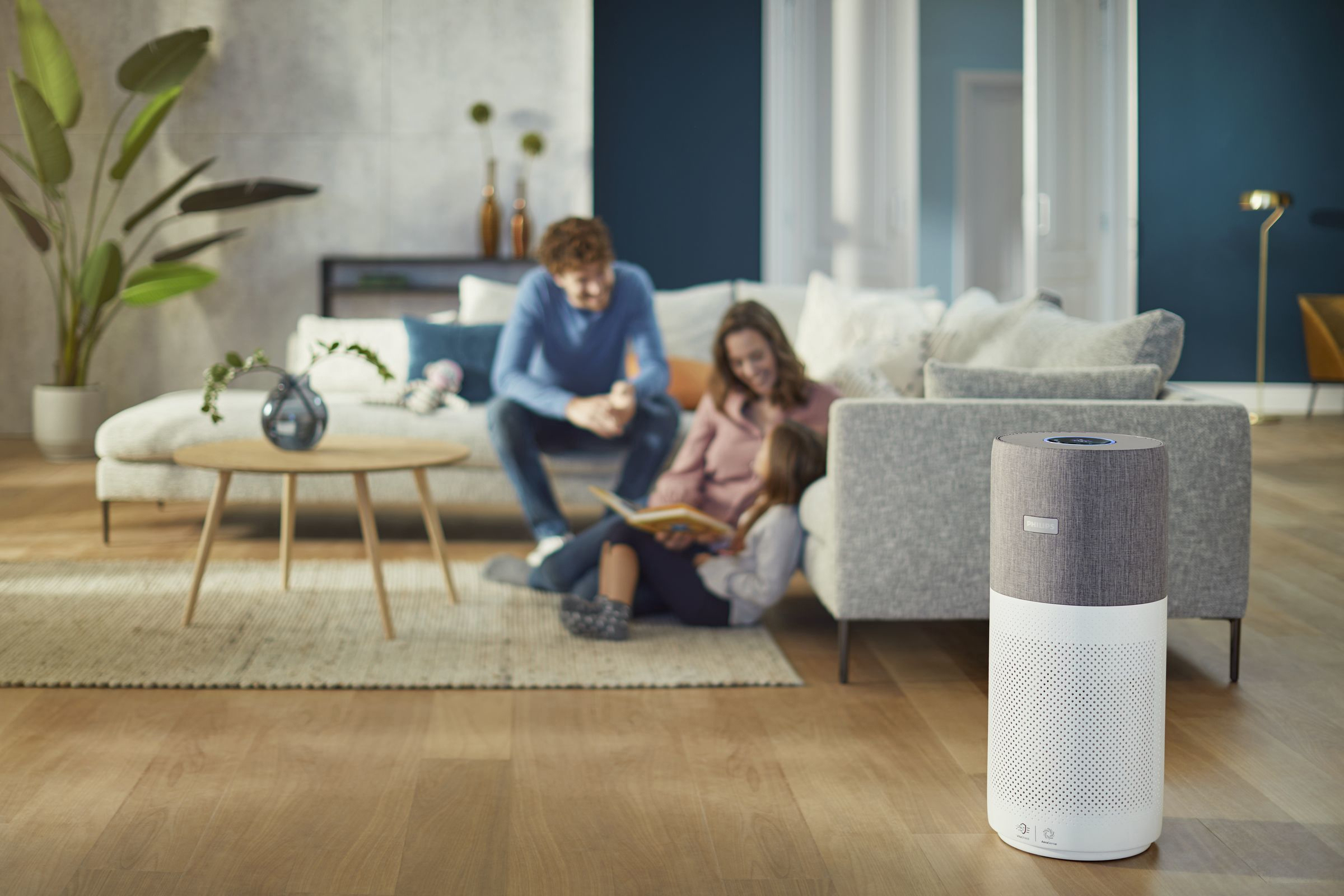 Familie im Wohnzimmer mit Luftreiniger auf dem Boden.