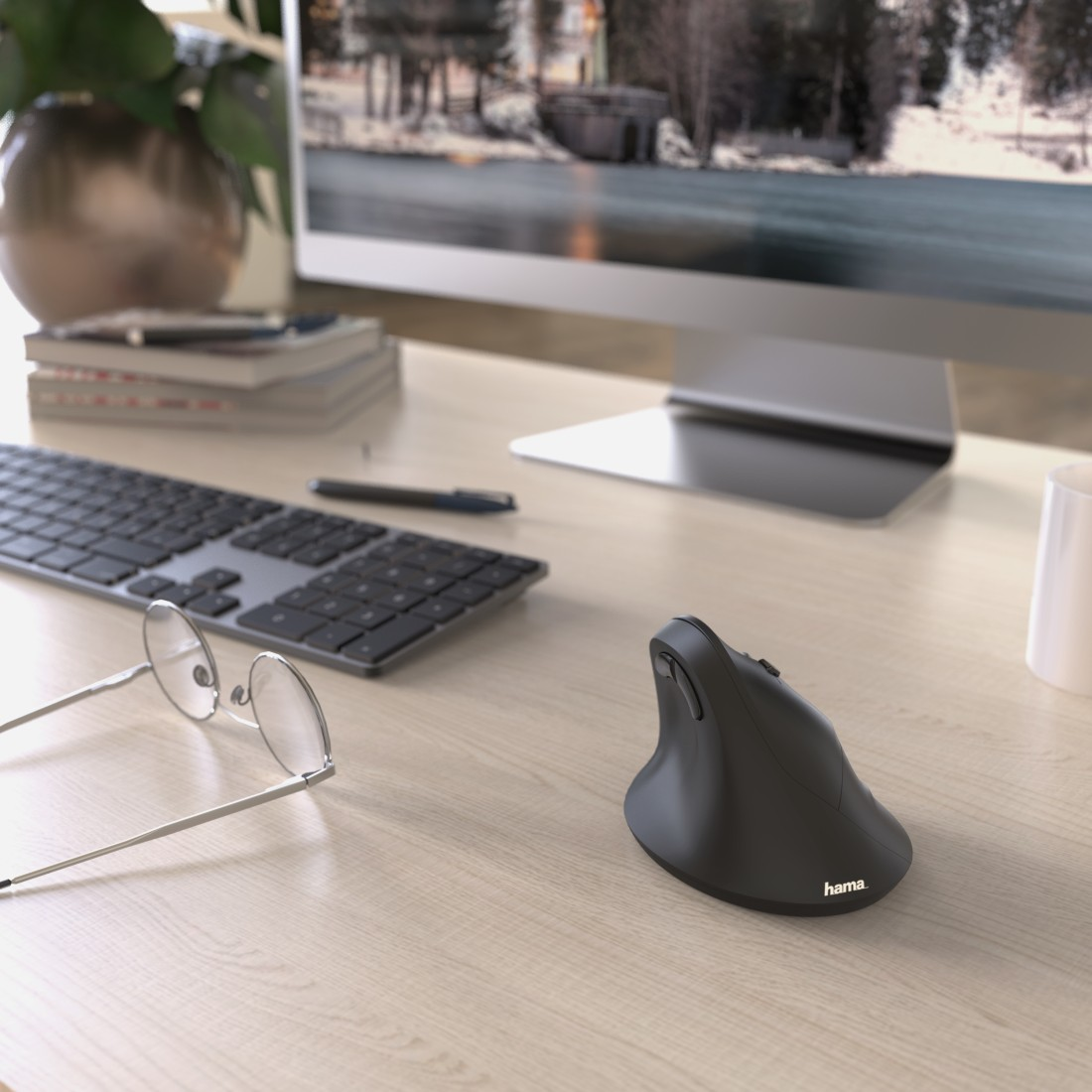 A desk with a computer monitor, keyboard, glasses, and ergonomic mouse. The setting is indoors.