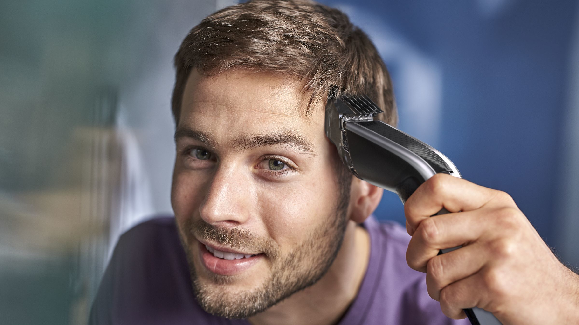 A man cutting his hair with a hair clipper.