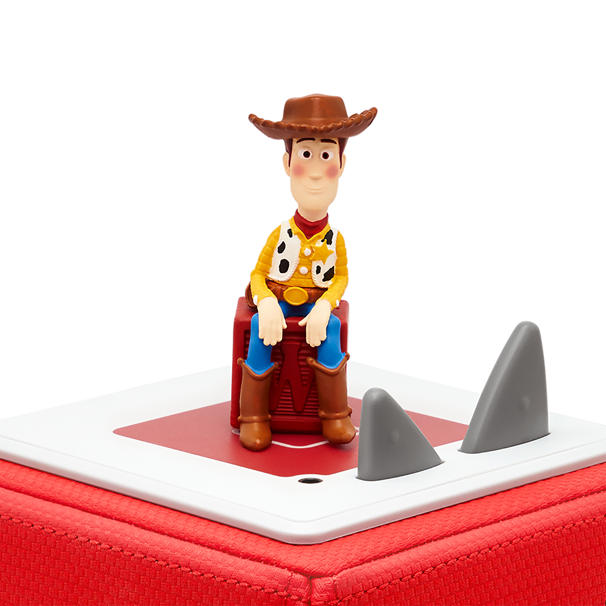 Toy Storys Woody-Puppe sitzt auf einem roten Block mit grauen Haifischflossen.