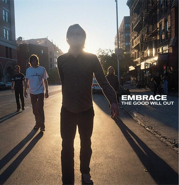 Pochette de l'album Embrace. Quatre hommes marchant dans la rue vers la caméra avec un coucher de soleil.