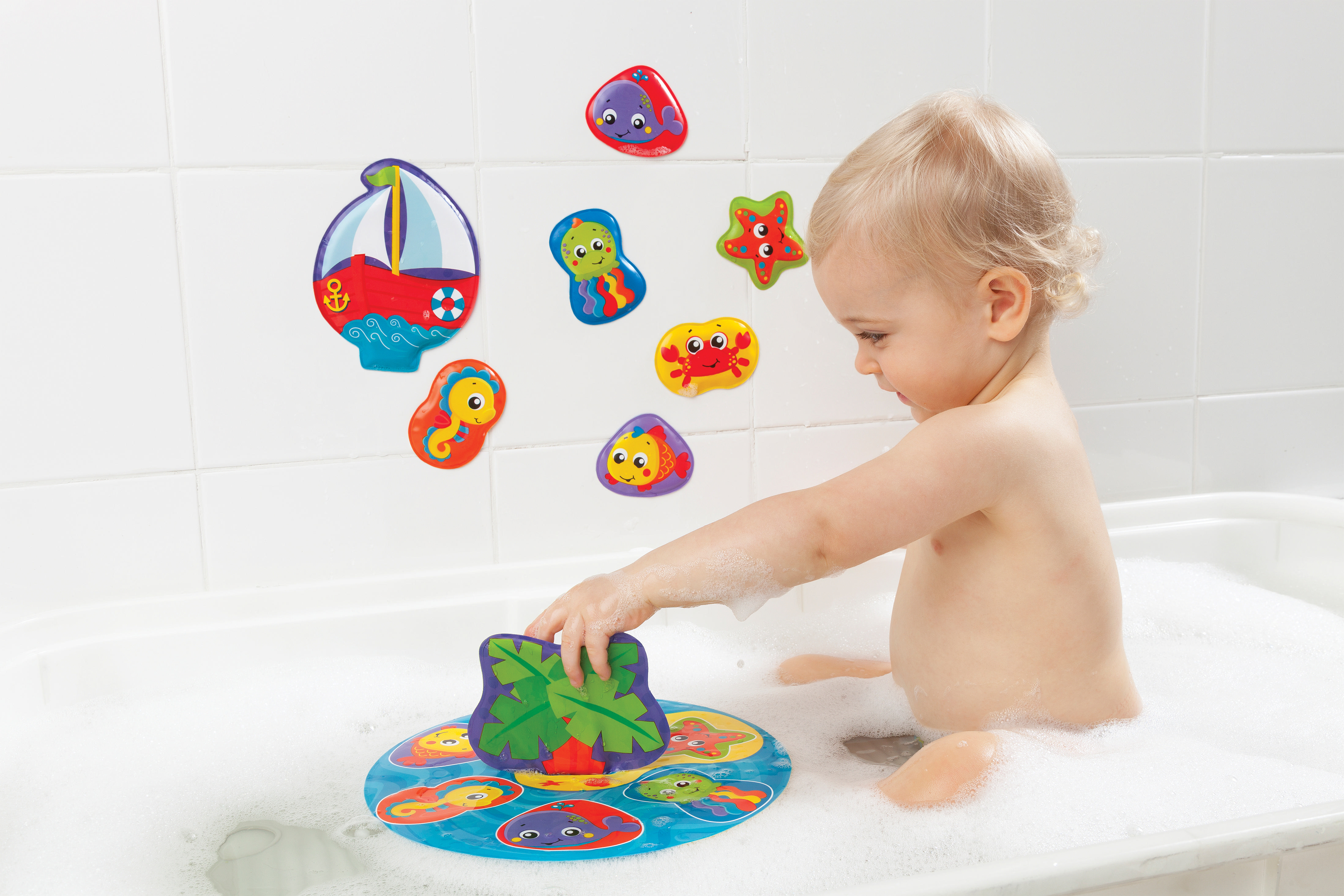 Ein Kind spielt mit Badespielzeug in einer Badewanne voller Blasen.