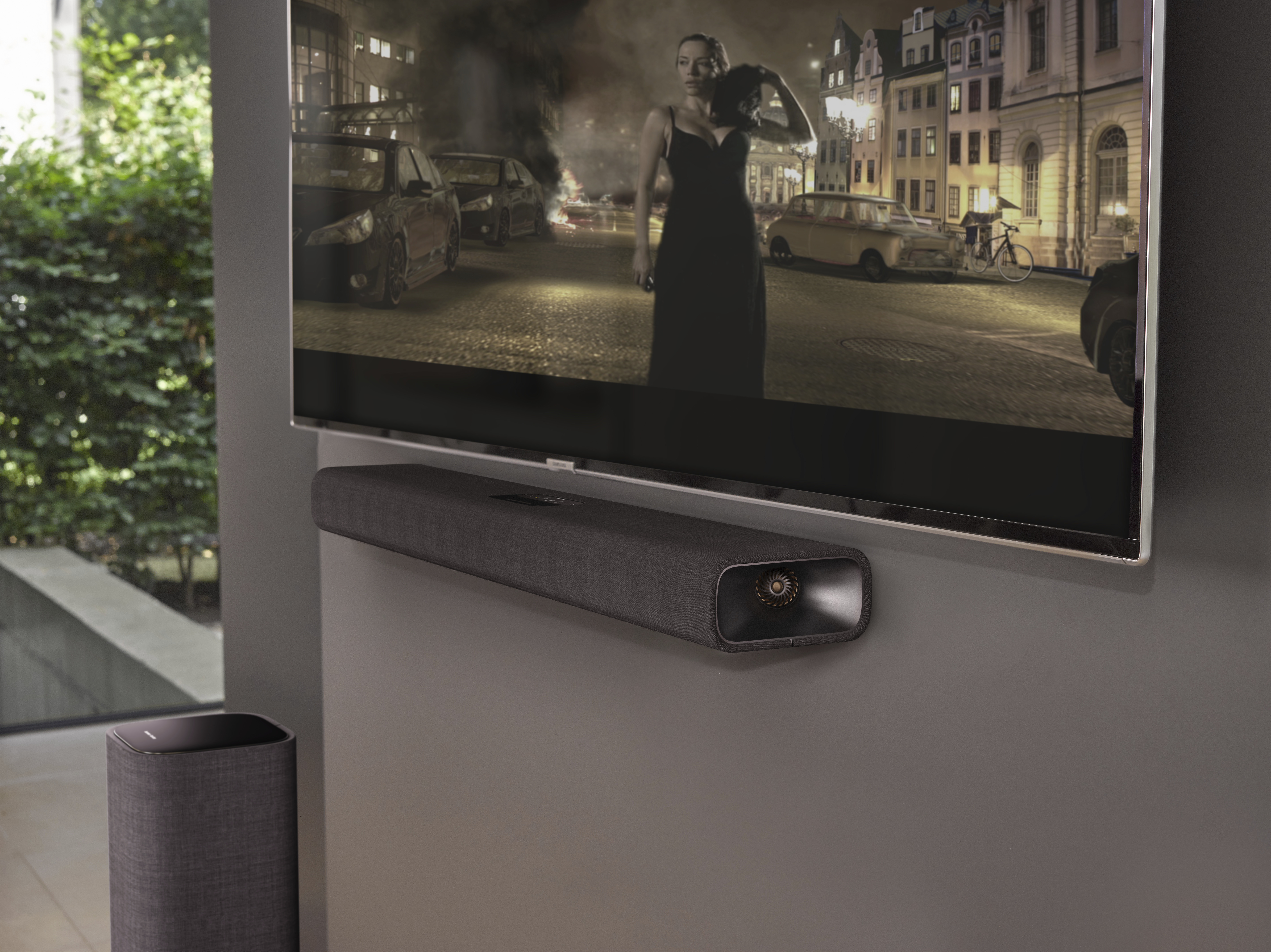 Een tv die een nachtscène weergeeft, met een soundbar eronder, aan de muur.