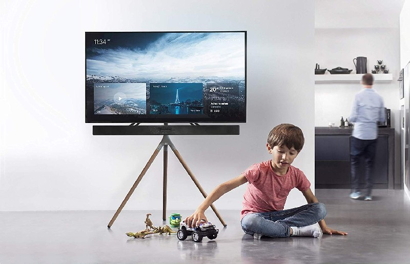 Una sala de estar moderna con un televisor en un trípode y un niño jugando con juguetes.