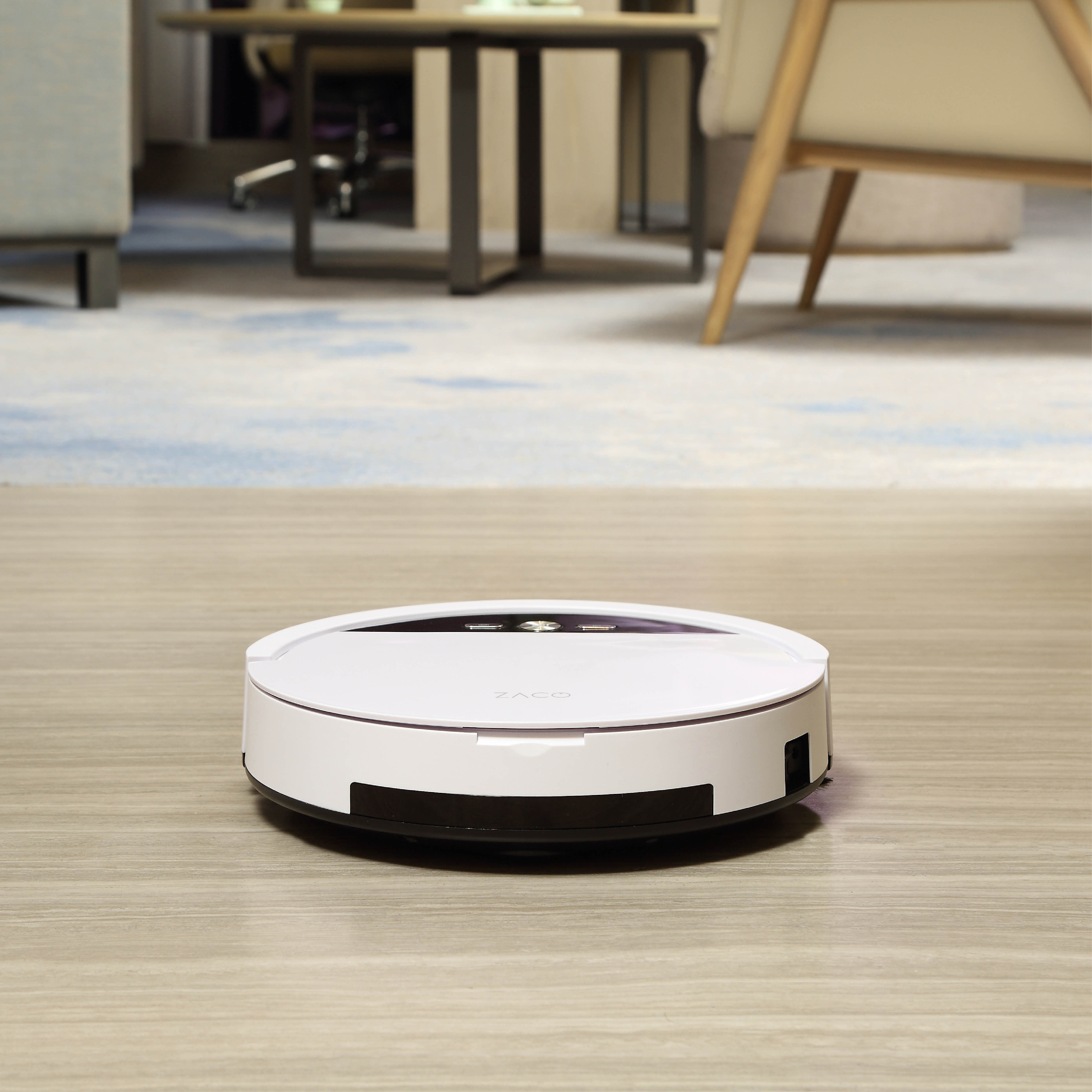 Weißer Roboter-Staubsauger auf einem Holzboden.