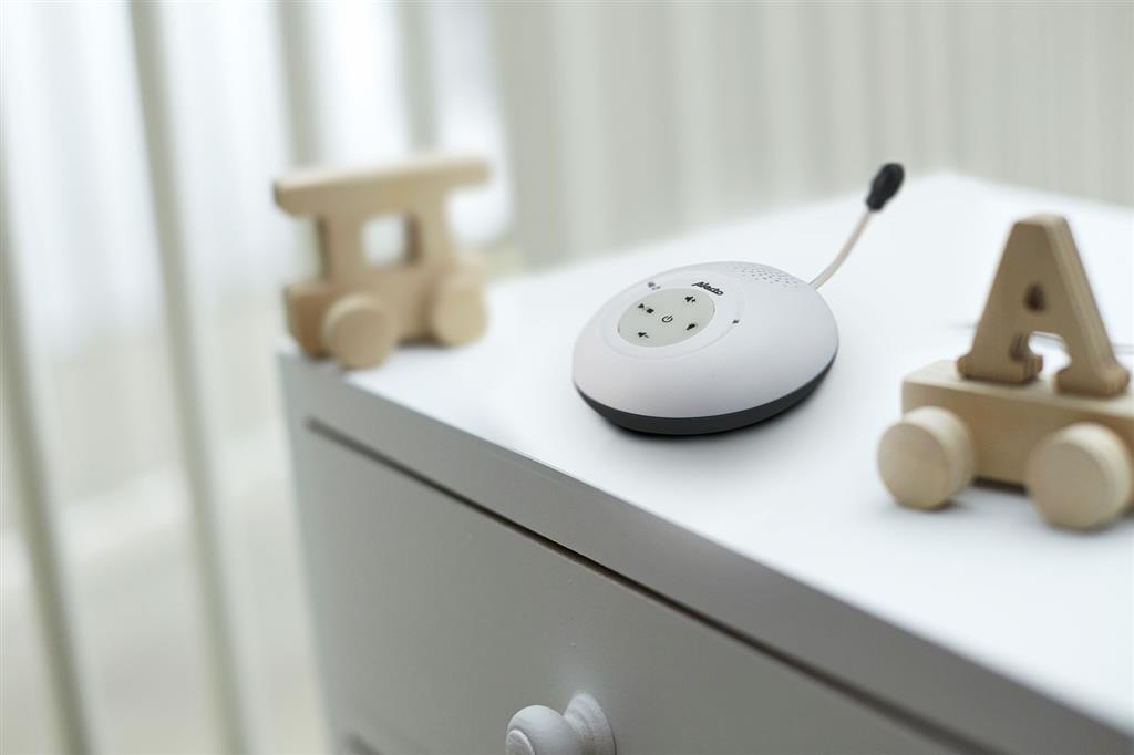 A baby monitor and wooden toys on a white dresser.