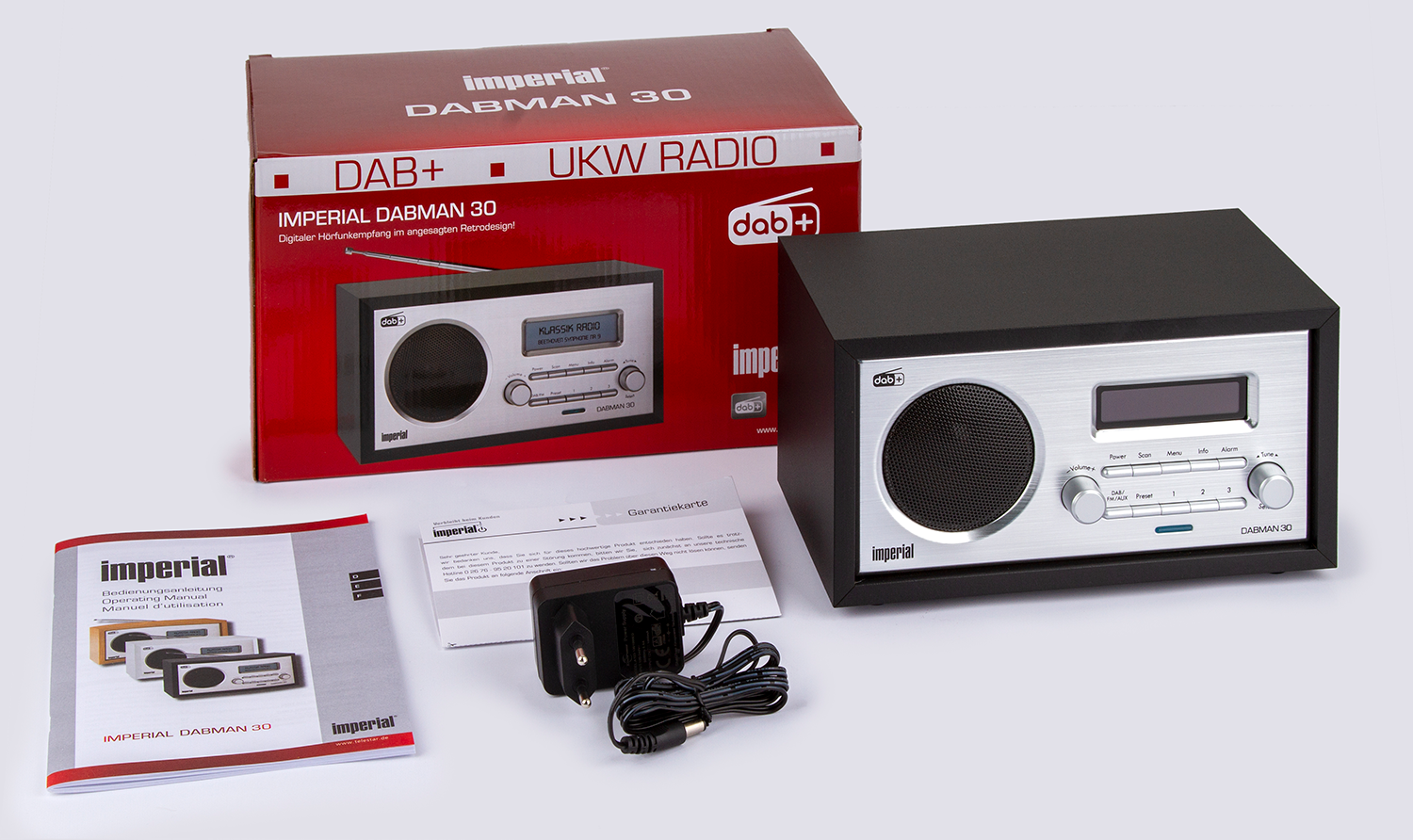 Een Imperial DABMAN 30 radio met accessoires, verpakking en een handleiding op een wit oppervlak.