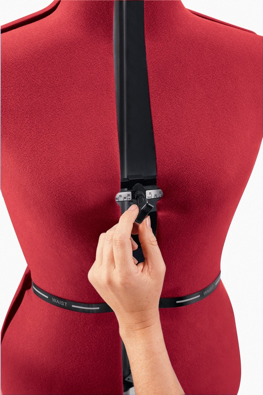 Person passt die Taille einer roten Schneiderpuppe mit einem schwarzen verstellbaren Stab an.