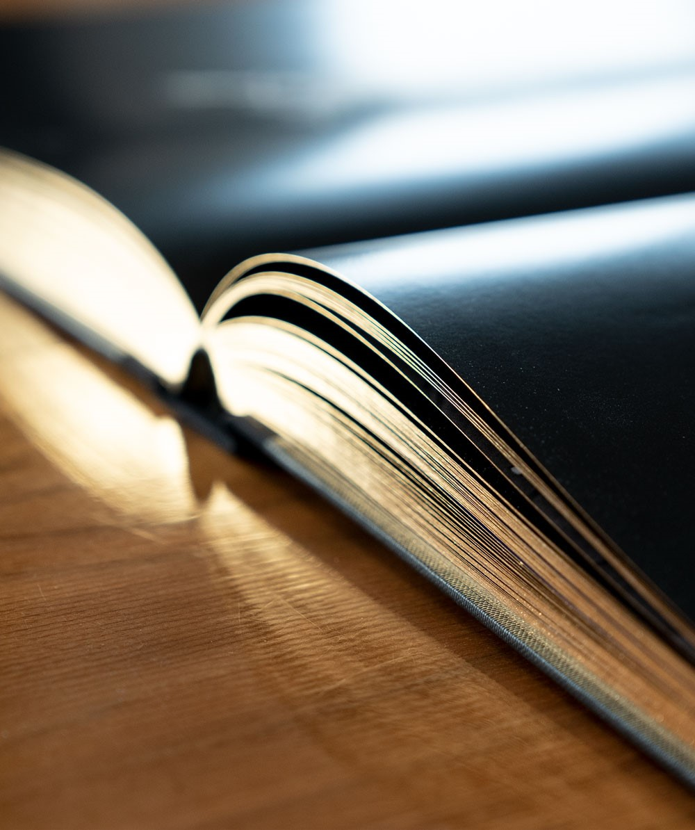 Nahaufnahme eines offenen Buches auf einer Holzoberfläche. Die Seiten sind schwarz.