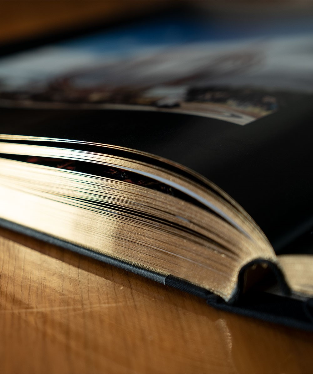 Offenes Buch mit goldfarbenen Seiten. Fokus auf den Seiten, auf einer Holzoberfläche.