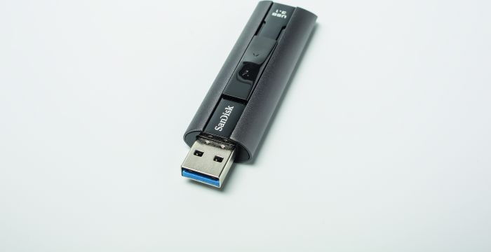 Ein schwarzer SanDisk USB-Stick mit blauem USB-Anschluss auf weißer Oberfläche.
