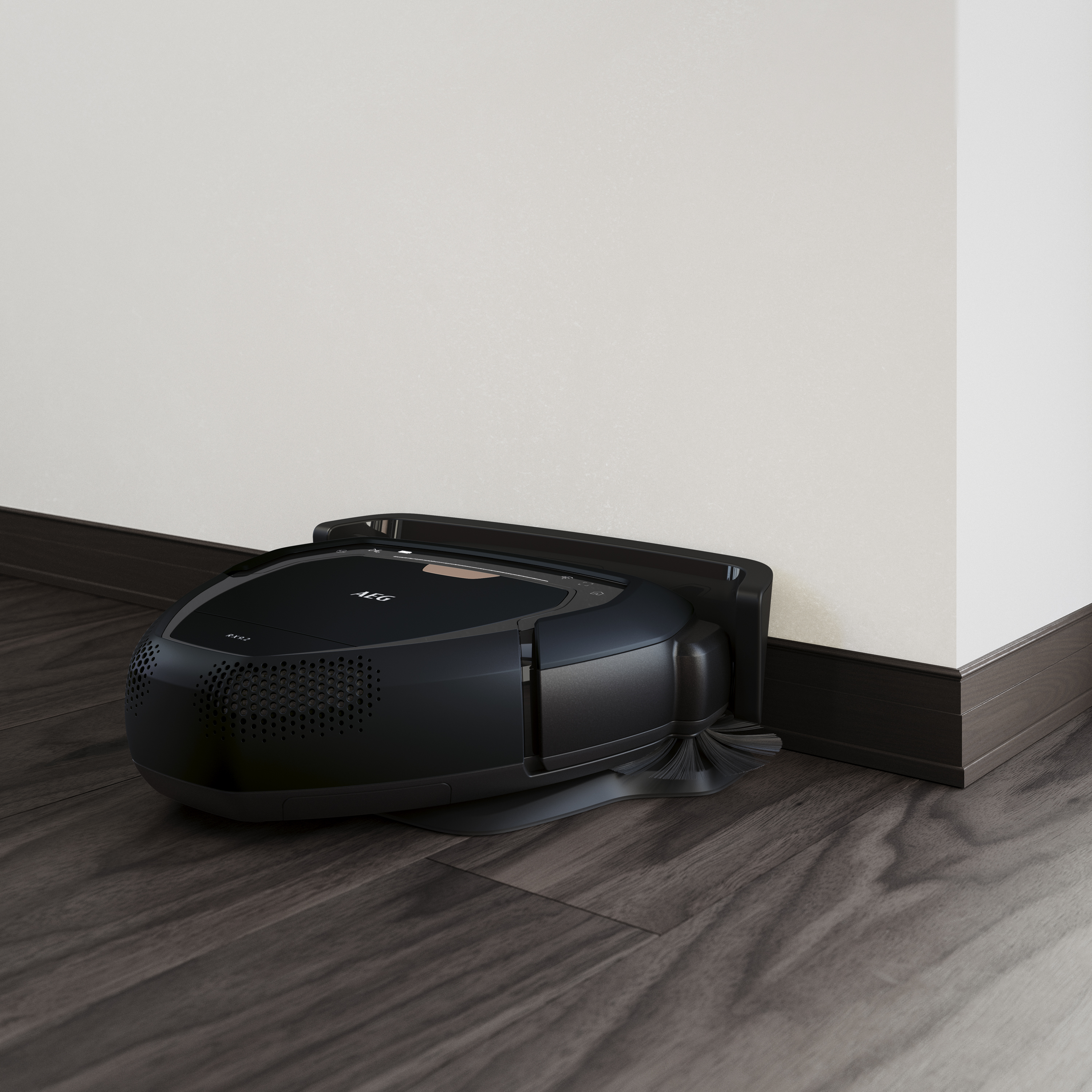 Een zwarte robotstofzuiger die tegen een muur en een houten vloer staat.