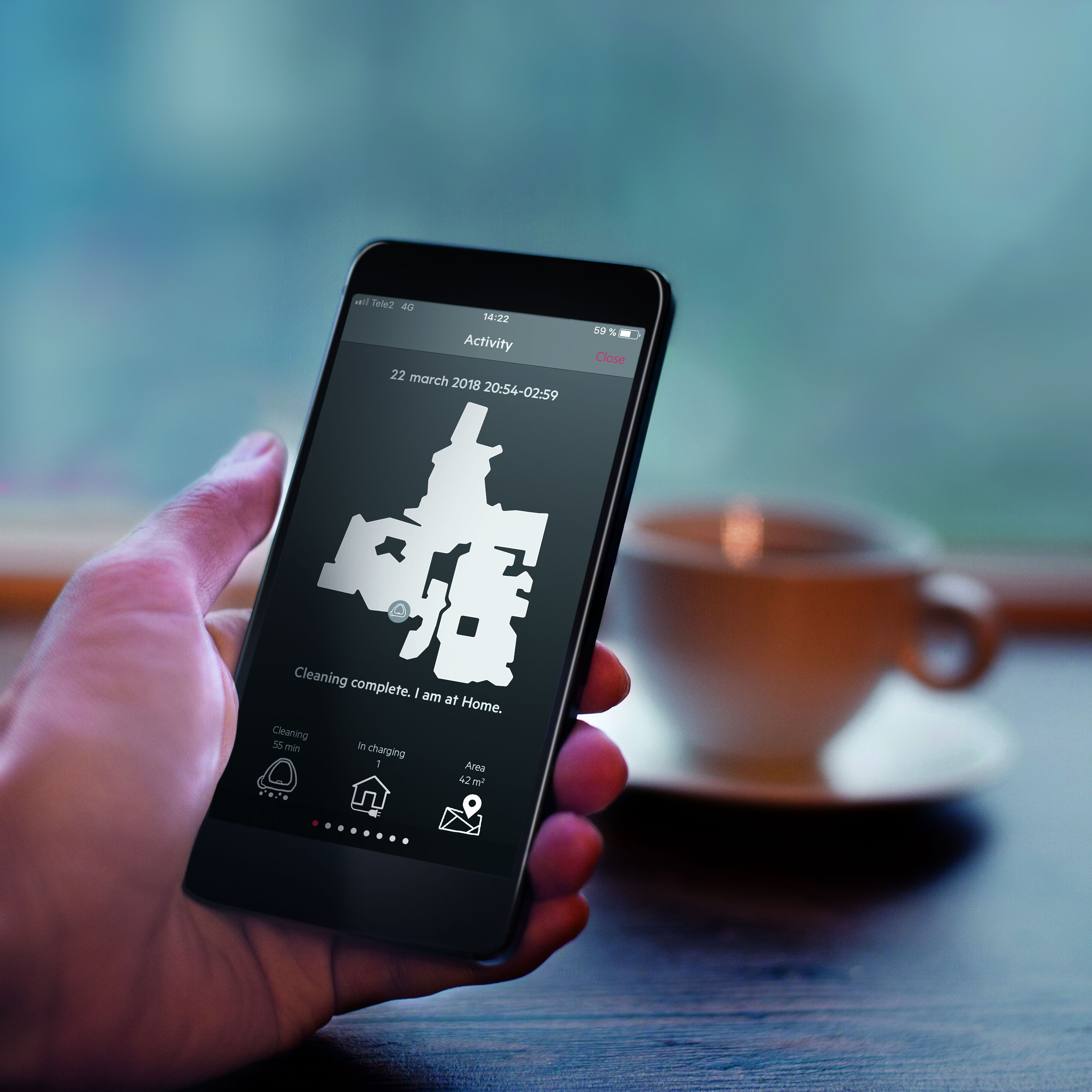 Een hand houdt een smartphone vast met een plattegrond, een kopje koffie op de achtergrond.