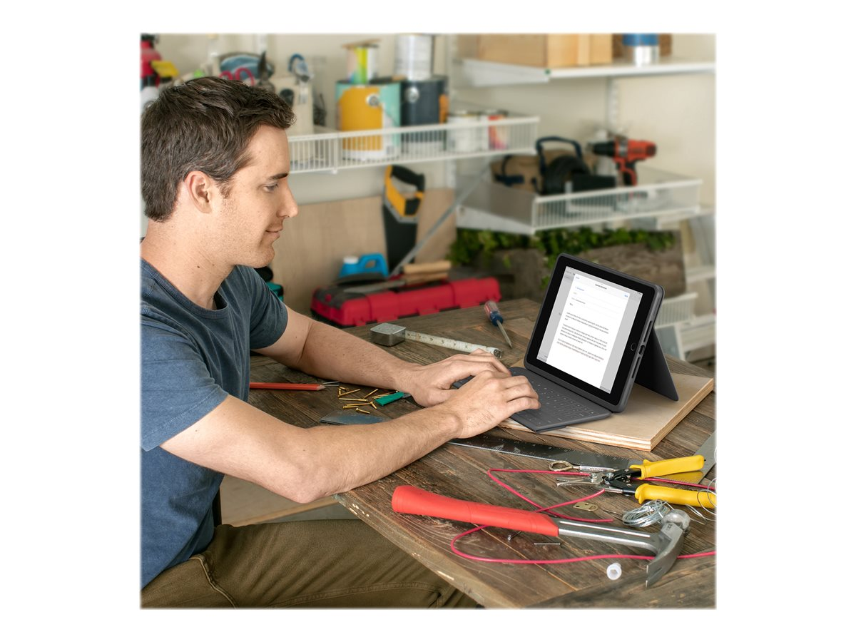Mann, der an einem Tablet an einem Holztisch arbeitet. Eine Werkzeugkiste und andere Werkzeuge liegen auf dem Tisch.
